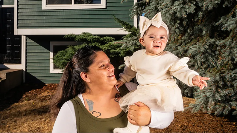 Photo of person holding a baby, outdoors — related to Alicia Oliver story 